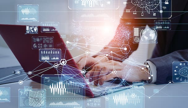 An employee's hands typing on a laptop with a digital overlay of graphs and data, illustrating machine learning in data management.