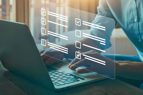 Employee feedback tools represented by hands typing on a laptop, overlayed with a graphic of checkboxes