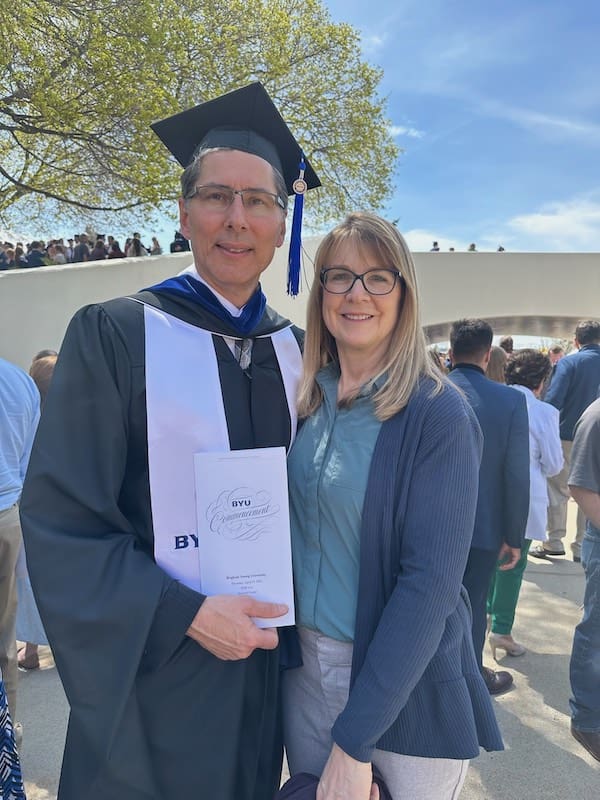 A culture of curiosity represented by Jon Dionne in graduation regalia, posing with his wife